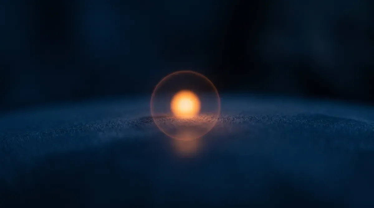 A single glowing orange point of light on a dark navy surface